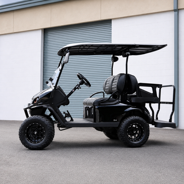 A black off-road electric golf cart with a four-passenger canopy, black tires, and a rear cargo bed, parked in front of a white building with a gray garage door.